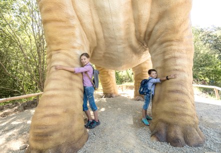 Kinder können die mächtigen Beine des Seismosaurus im Dinosaurierpark Teufelsschlucht kaum umfassen, © Felsenland Südeifel Tourismus GmbH / Dominik Ketz